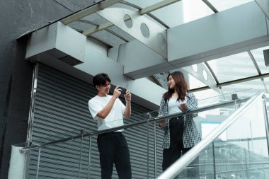 Siyah beyaz giysili bir barikattaki kız arkadaşı için fotoğraf çeken bir kız, erkeğine gülümseyen bir kız..