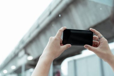 Yükselen akıllı telefonun kesilmiş görüntüsü gökyüzü treninin demiryolunun fotoğrafını çekiyor..