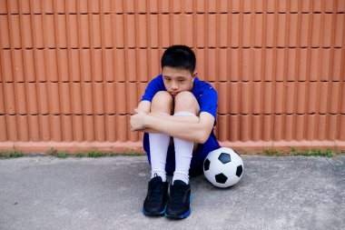 Yalnız çocuk ve futbol topu kahverengi duvarda ailesini bekliyor..