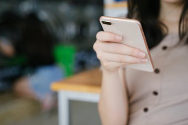 Çamaşırhanede kıyafetlerini beklerken kızın elindeki akıllı telefonun kesilmiş görüntüsü. Boşluğu kopyala..