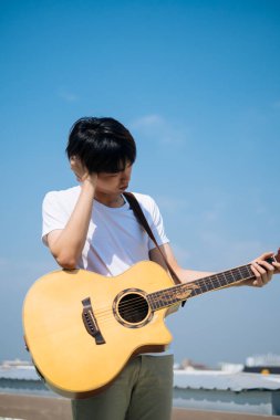 Genç Taylandlı gitarist akustik gitar çalma konusunda sorun yaşıyor..