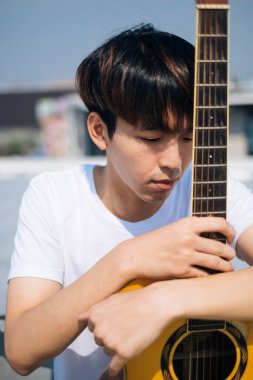 Akustik gitaristli yakışıklı Taylandlı genç bir adamın portresi..