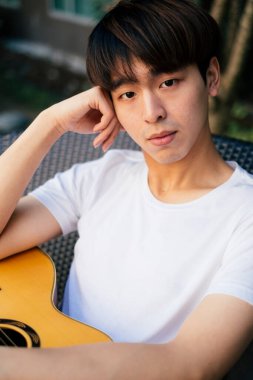 Akustik gitaristli yakışıklı Taylandlı genç bir adamın portresi..