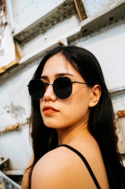 Makarna askılı ve enkaz uçağının önünde pembe etekli siyah uzun saçlı kızın portresi..