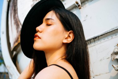 Siyah, uzun saçlı kız enkaz uçağının önünde duruyor şapkayı yüzünden çek..