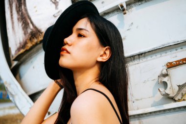 Siyah, uzun saçlı kız enkaz uçağının önünde duruyor şapkayı yüzünden çek..