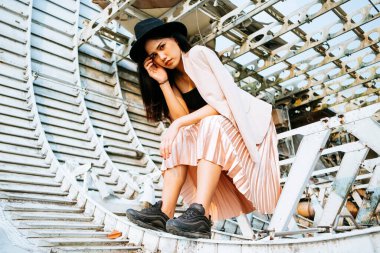 Siyah uzun saçlı kız mavi gökyüzünün altında siyah şapkalı enkaz uçakta oturuyor..