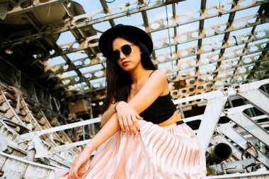 Siyah ve pembe elbiseli uzun saçlı kız enkaz uçağında oturuyor..