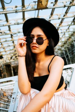 Siyah ve pembe elbiseli uzun saçlı kız enkaz uçağında oturuyor..