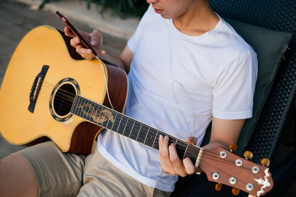 Молодой Тайский Гитарист Слушает Музыку Наушниками Используя Смартфон Тренировки Гитары Стоковое Фото