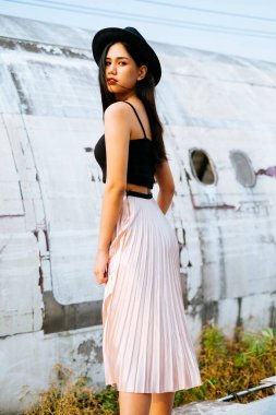 Siyah ve pembe elbiseli uzun saçlı kadın. Terk edilmiş bölgede uçak enkazının yanında güzel bir duruş sergiledi..