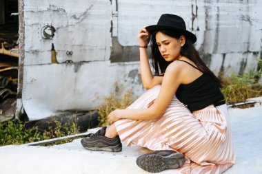 Siyah ve pembe elbiseli kadın terk edilmiş bölgede uçak enkazı için tek başına oturuyor..