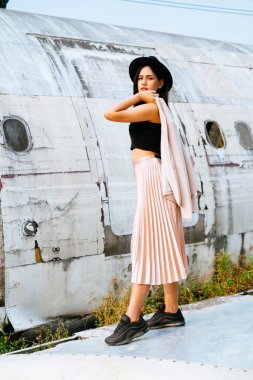 Siyah ve pembe elbiseli kadın enkaz uçağının yanında yürüyor..