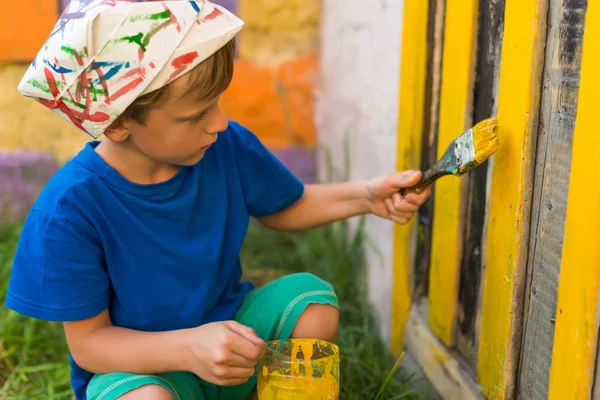 Boy performs painting works paint outdoors summer Royalty Free Stock Images