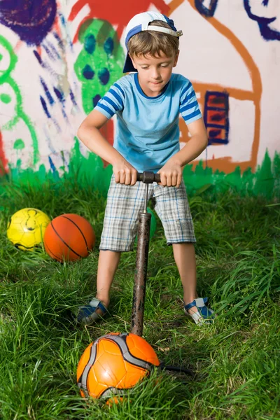 Хлопчик надуває футбольний м'яч насос — стокове фото