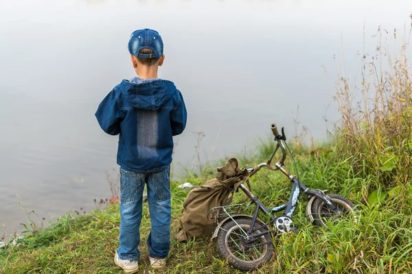 Ragazzo viaggia con uno zaino sulla riva del fiume — Foto Stock