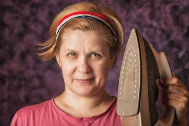 40 yıllık kadın. Çarşaf okşamak için demiri tutuyor. Birini yakmakla tehdit ediyor. Soyut arkaplan. Stüdyo çekimi.