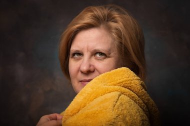 Yüzünde duygu olan bir adamın fotoğrafı. Ev eşyaları sarı renktedir. Sıcak bornoz kurtuluşu soğuktan.