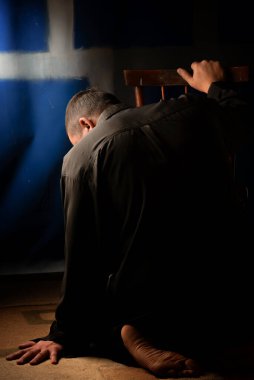 Zor bir duygusal durumda olan bir erkek. Yalınayak elini yerde dinlendirdi. Bu durumdan kurtulmak için kalan rezervleri değerlendirir. Her zaman umut vardır. Karanlık bir odada bir ışık huzmesi.