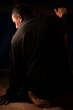 Zor bir duygusal durumda olan bir erkek. Yalınayak elini yerde dinlendirdi. Bu durumdan kurtulmak için kalan rezervleri değerlendirir. Her zaman umut vardır. Karanlık bir odada bir ışık huzmesi.