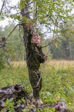 The boy in wood with a stick in a hand