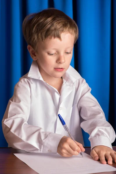 Chłopiec zapisuje na kartce papieru — Zdjęcie stockowe
