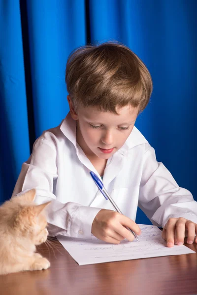 Junge schreibt auf ein Blatt Papier — Stockfoto