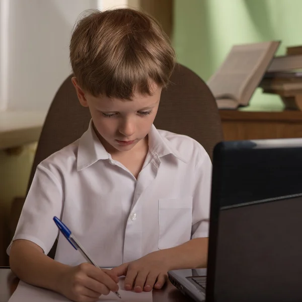 Jongen met laptop aan tafel — Stockfoto