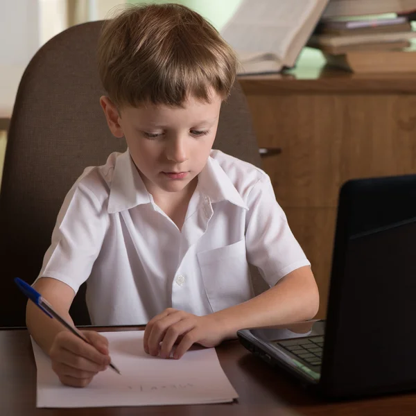 Jongen met laptop aan tafel — Stockfoto