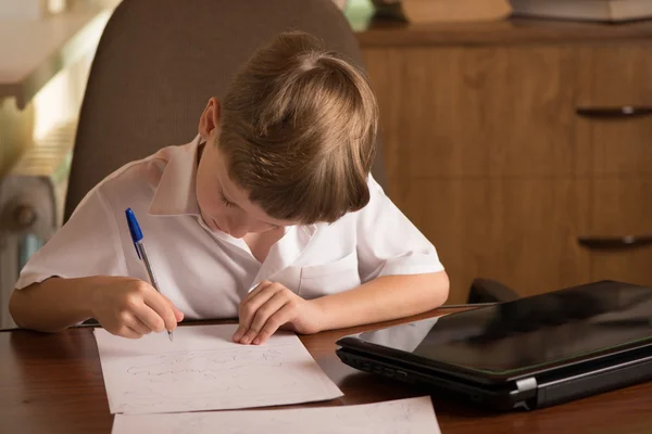 Jongen met laptop aan tafel — Stockfoto