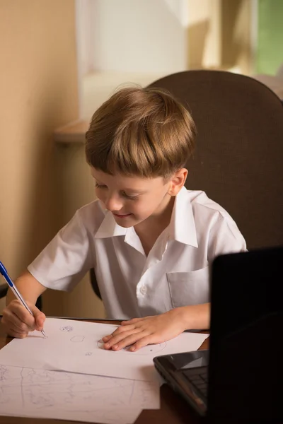 Jongen met laptop aan tafel — Stockfoto