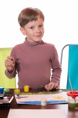 Çocuk bir sulu boya bir kağıda bir fırça çekti.
