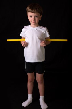 Çocuk atlet spor salonunda egzersiz jimnastik sopayla gerçekleştirir