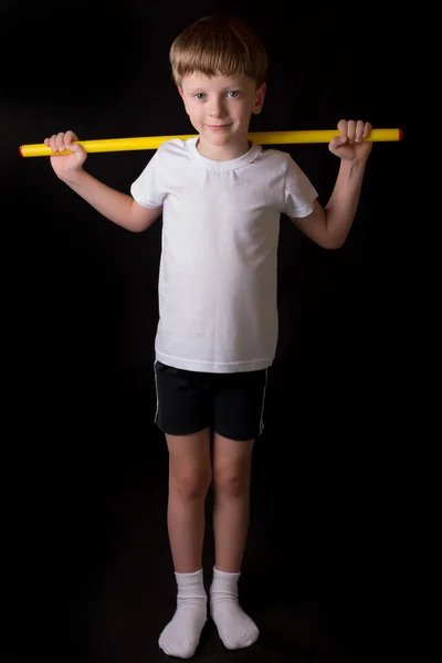 男孩的运动员在健身房里执行练习体操棒 — 图库照片