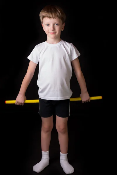 Niño atleta realiza ejercicios con palo de gimnasia en el gimnasio — Foto de Stock