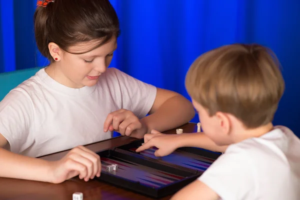Мальчик и девочка играют в настольную игру под названием нарды — стоковое фото