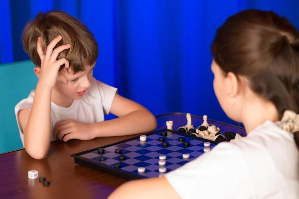 Мальчик и девочка играют в настольную игру "Шашки" — стоковое фото