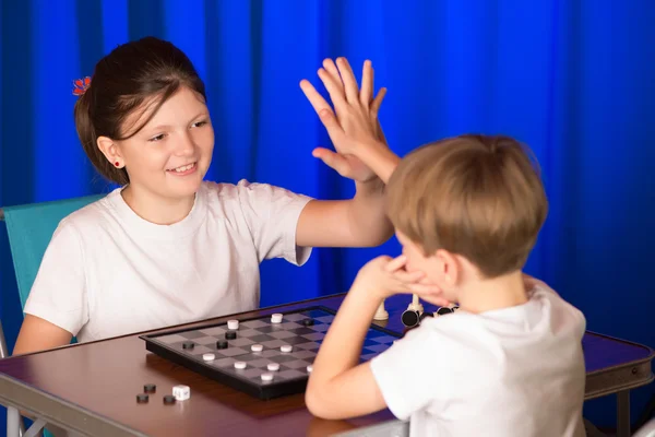 Enfants garçon et fille jouer à un jeu de société appelé Checkers — Photo