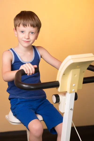 Il bambino è addestrato su una bici stazionaria. Stile di vita sano . — Foto Stock