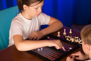 Boy and girl playing a board game called Backgammon clipart