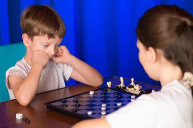Children boy and girl playing a board game called Checkers clipart