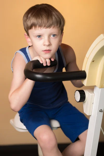 Il bambino è addestrato su una bici stazionaria. Stile di vita sano . — Foto Stock