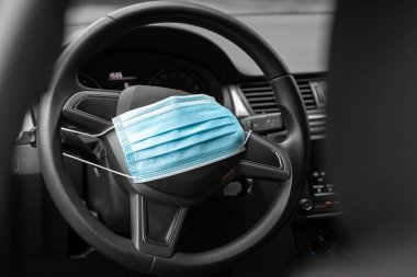 Mavi tıbbi maske bir arabanın direksiyonunda. Covid-19 ve Coronavirus hastalığı kavramı