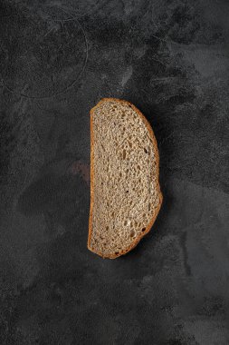 slice of gray bread on a black textured background, top view
