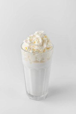 Beyaz milkshake ve kremalı cam gri arka planda doğal gölgeler