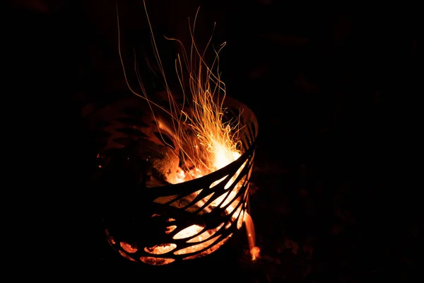 Gece karanlığında üzerinde odun parçası olan bir kamp ateşinin uzun pozlu fotoğrafı.