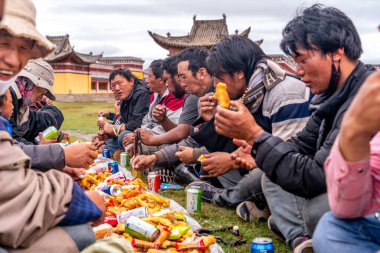 Sichuan / Çin-08.04.2020: İnsanlar kutsal festivali küçük uzak Budist manastırında kutluyor, geleneksel Tibet elbisesi içinde oturup yemek yiyorlar