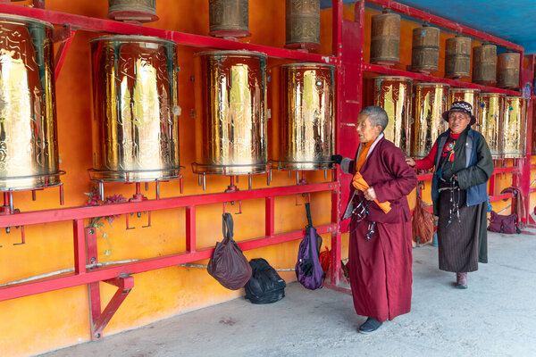 Сычуань / Китай-08.04.2020: Золотые катящиеся молитвенные барабаны в тибетском буддийском монастыре в Шангри-ла