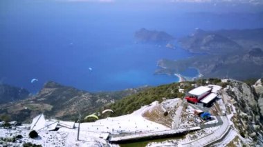 Türkiye 'nin Fethiye kentindeki Oludeniz' de paraşüt sporu için dünyaca ünlü yamaç paraşütü paraşütü ve paraşüt paraşütü noktası üzerine inanılmaz yüksek açılı insansız hava aracı manzarası