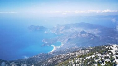 Türkiye 'nin Fethiye kentindeki Oludeniz' de paraşüt sporu için dünyaca ünlü yamaç paraşütü paraşütü ve paraşüt paraşütü noktası üzerine inanılmaz yüksek açılı insansız hava aracı manzarası